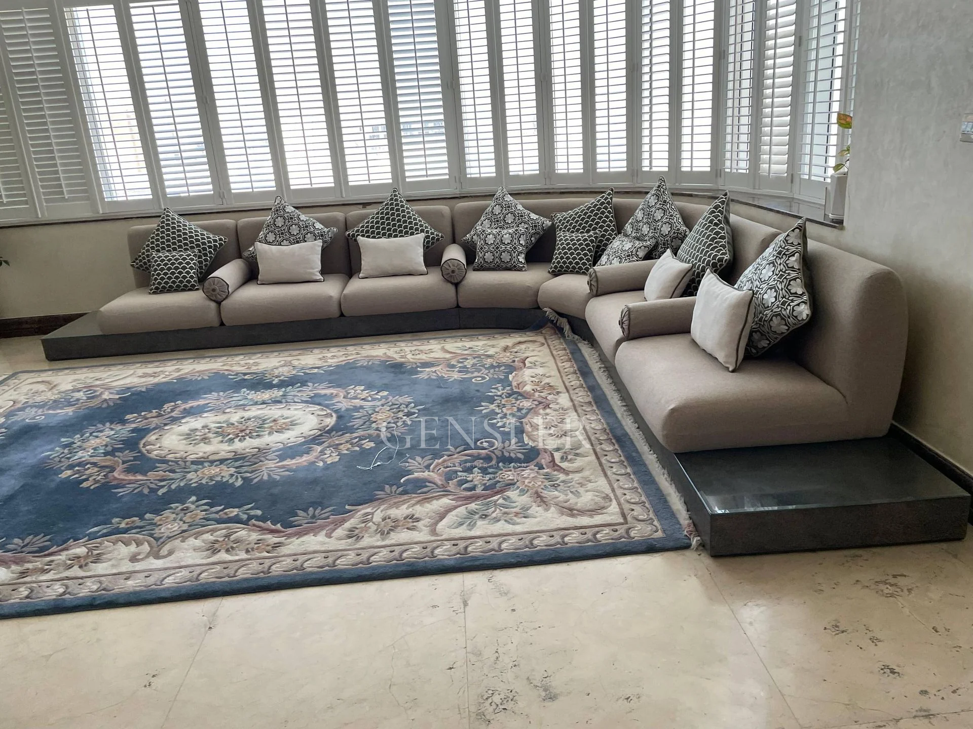 Close view of patterned cushions and low seating beside the blue rug.
