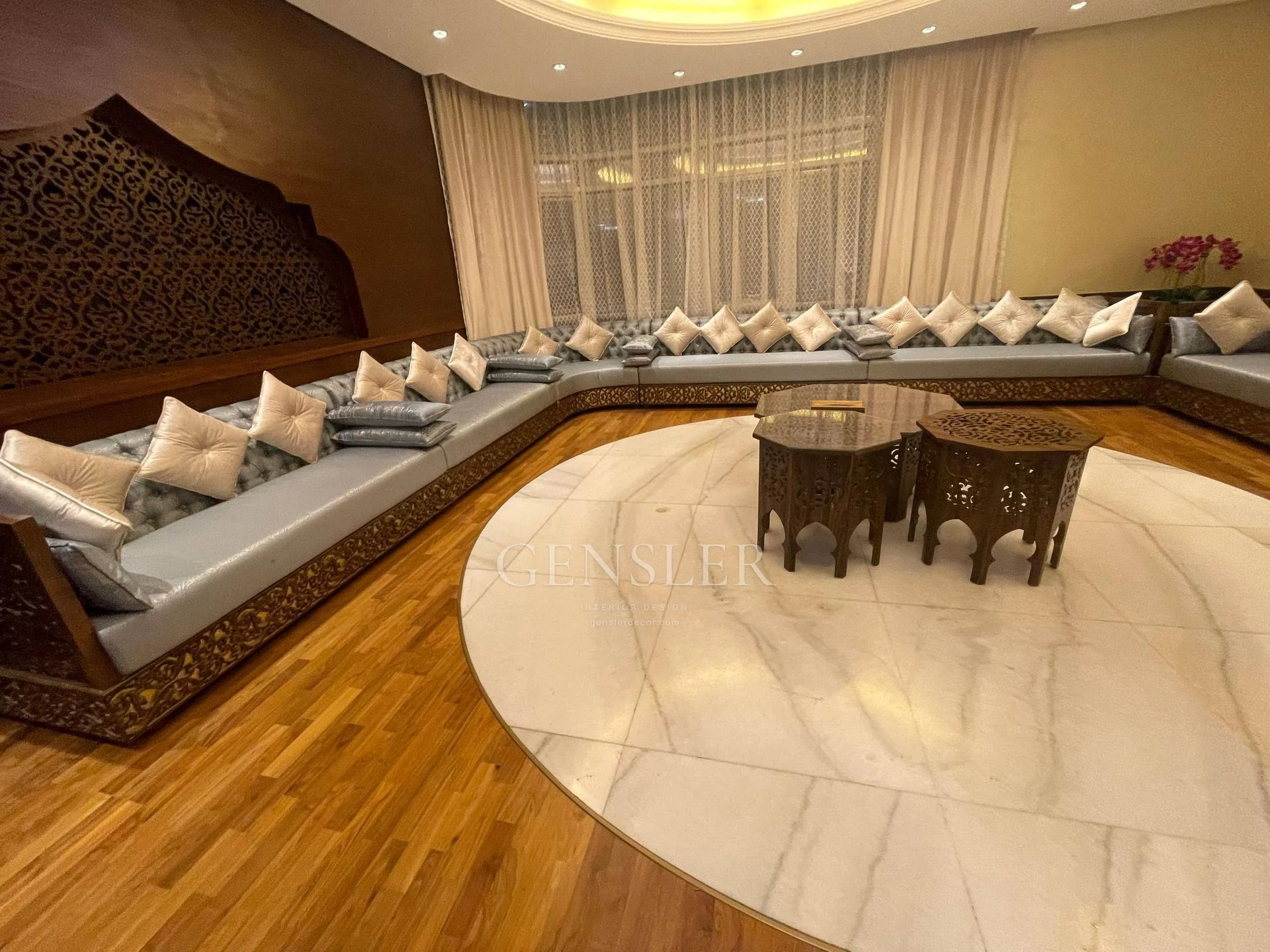 Traditional grey majlis with decorative brown bases and an ornate wall.