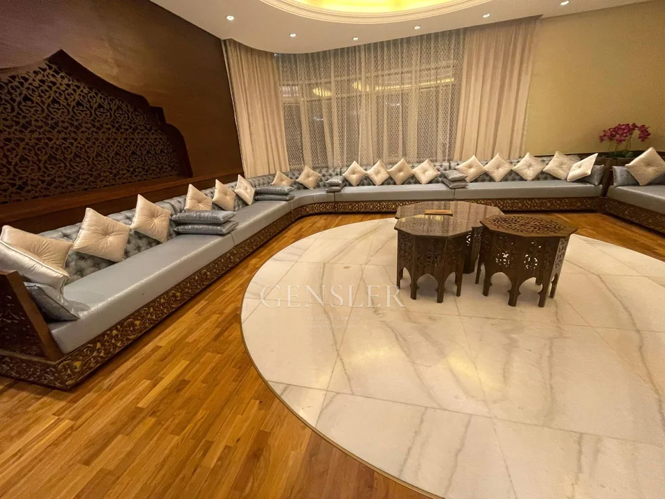 Traditional grey majlis with decorative brown bases and an ornate wall.