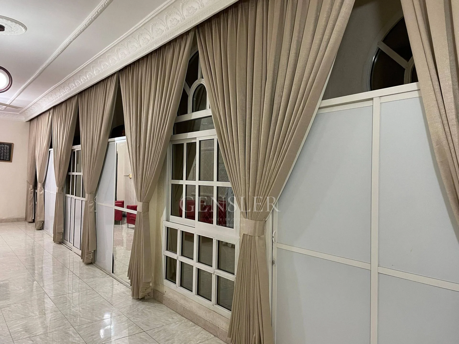 Repeated beige curtain panels along a wall of arched windows.