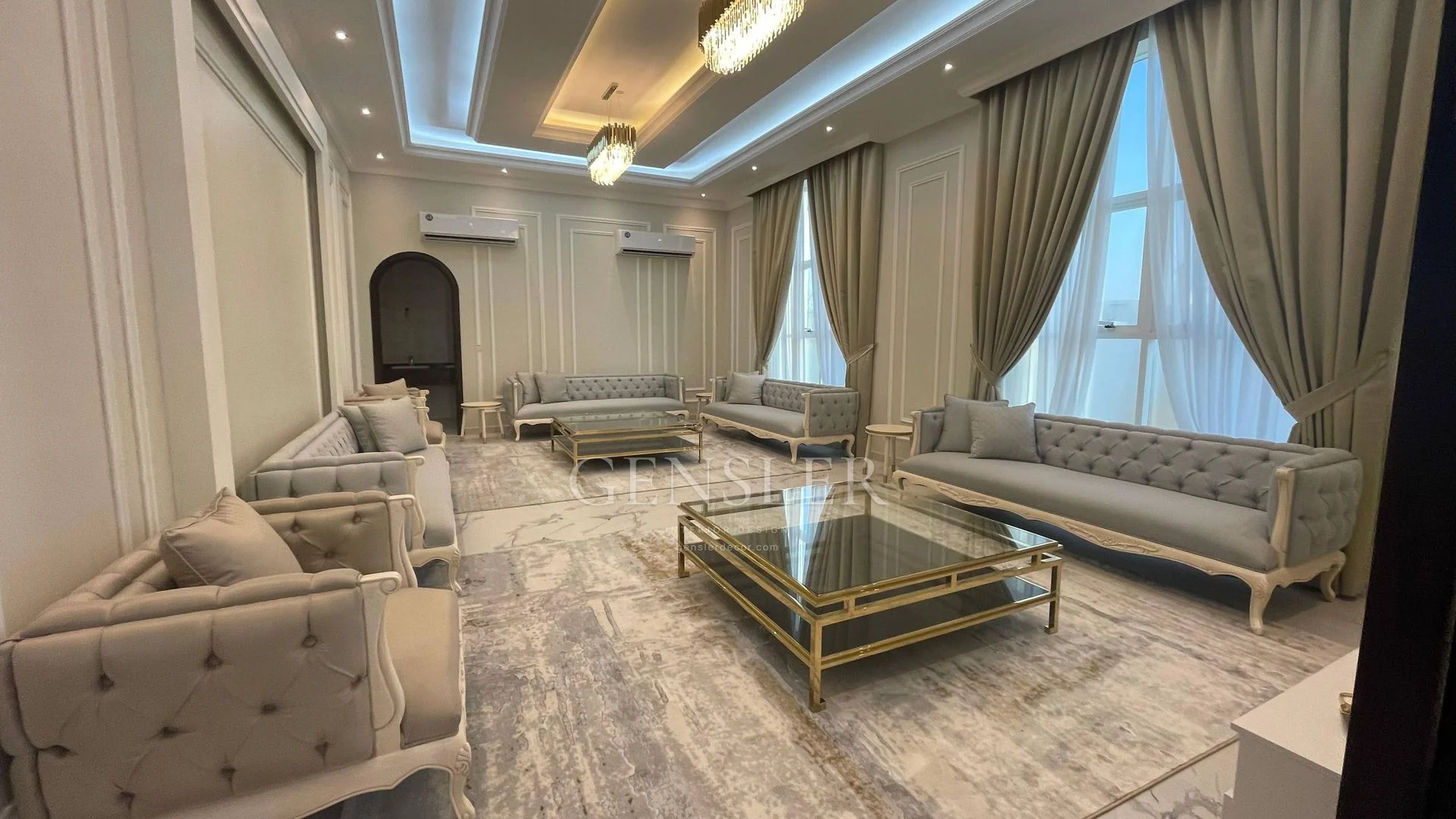 Classic tufted seating and glass-top tables beneath layered ceiling light.