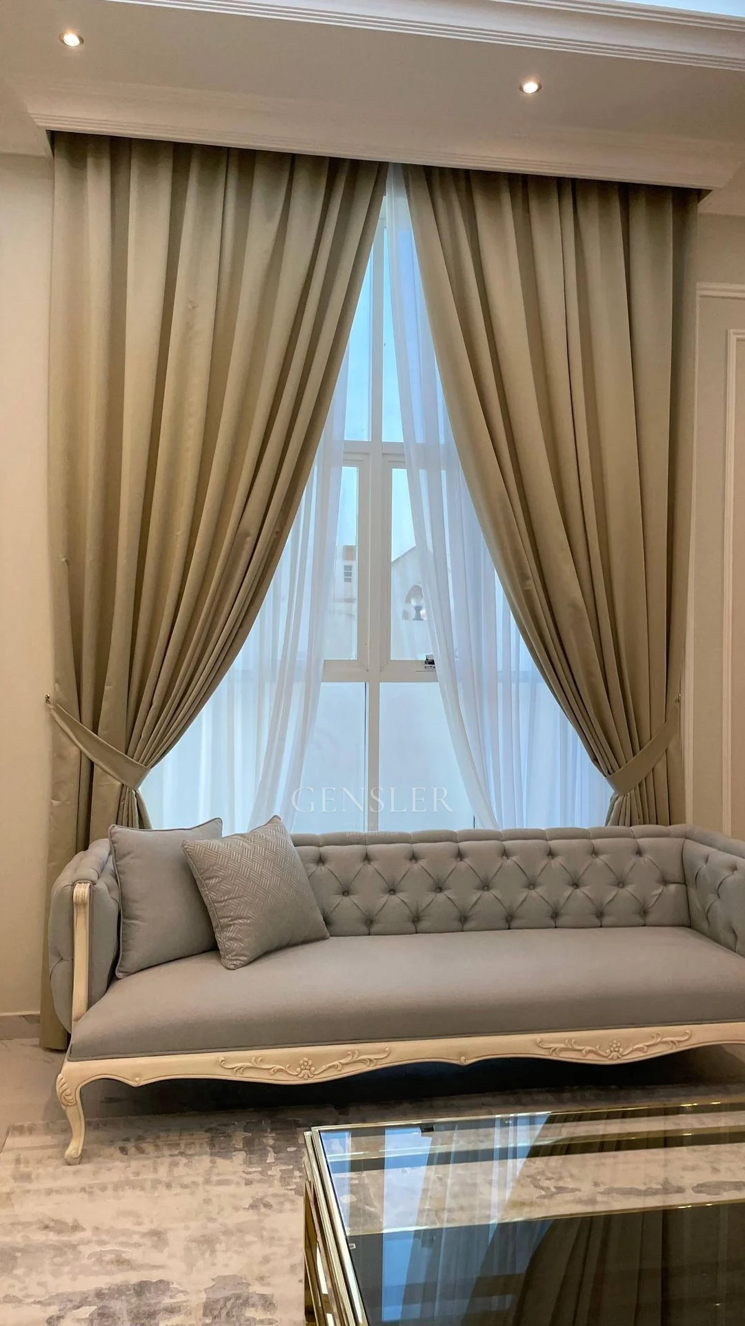 Pale tufted sofa beneath tall tied-back curtains.