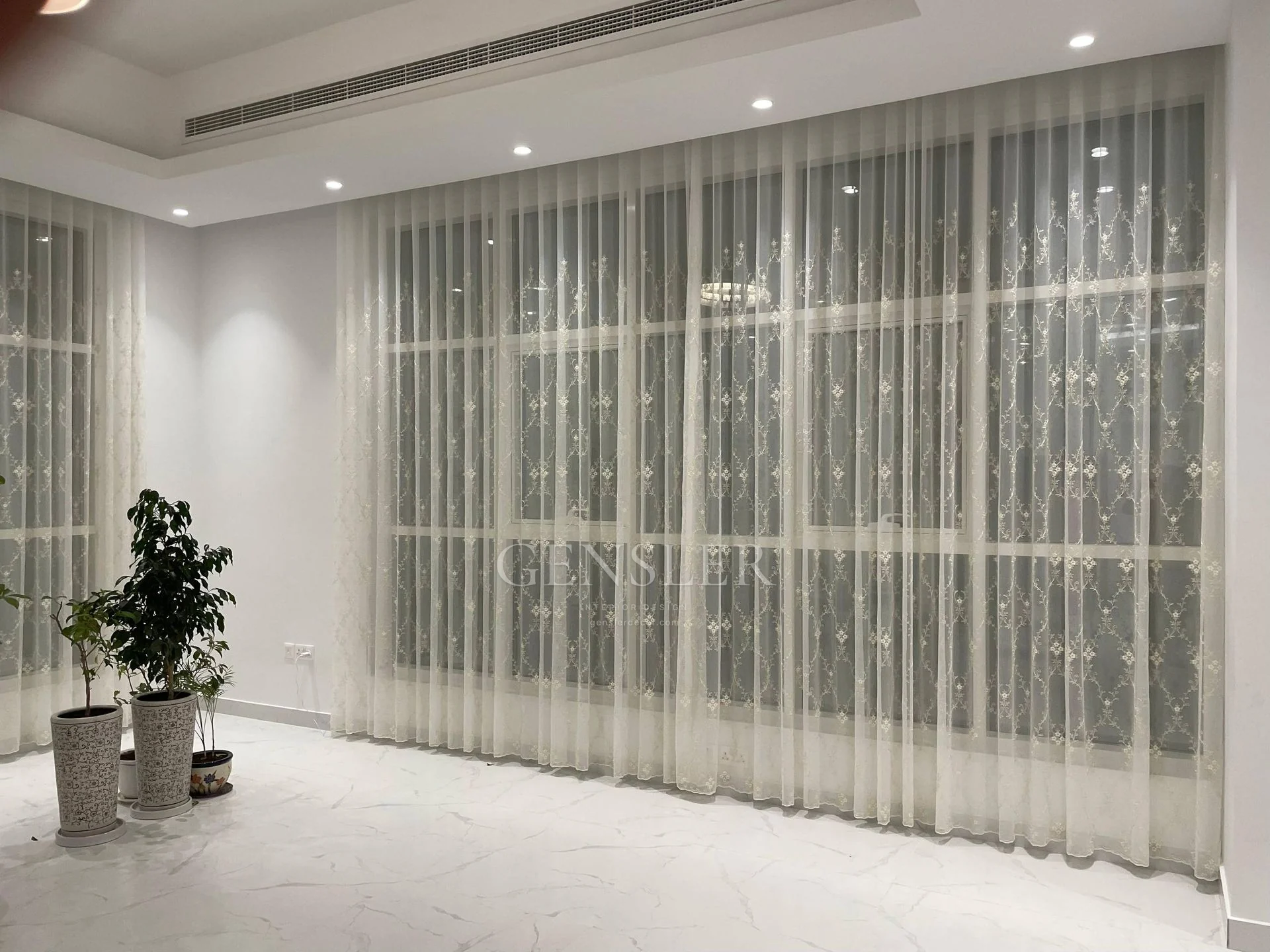 White patterned sheers spanning a wide glazed wall.