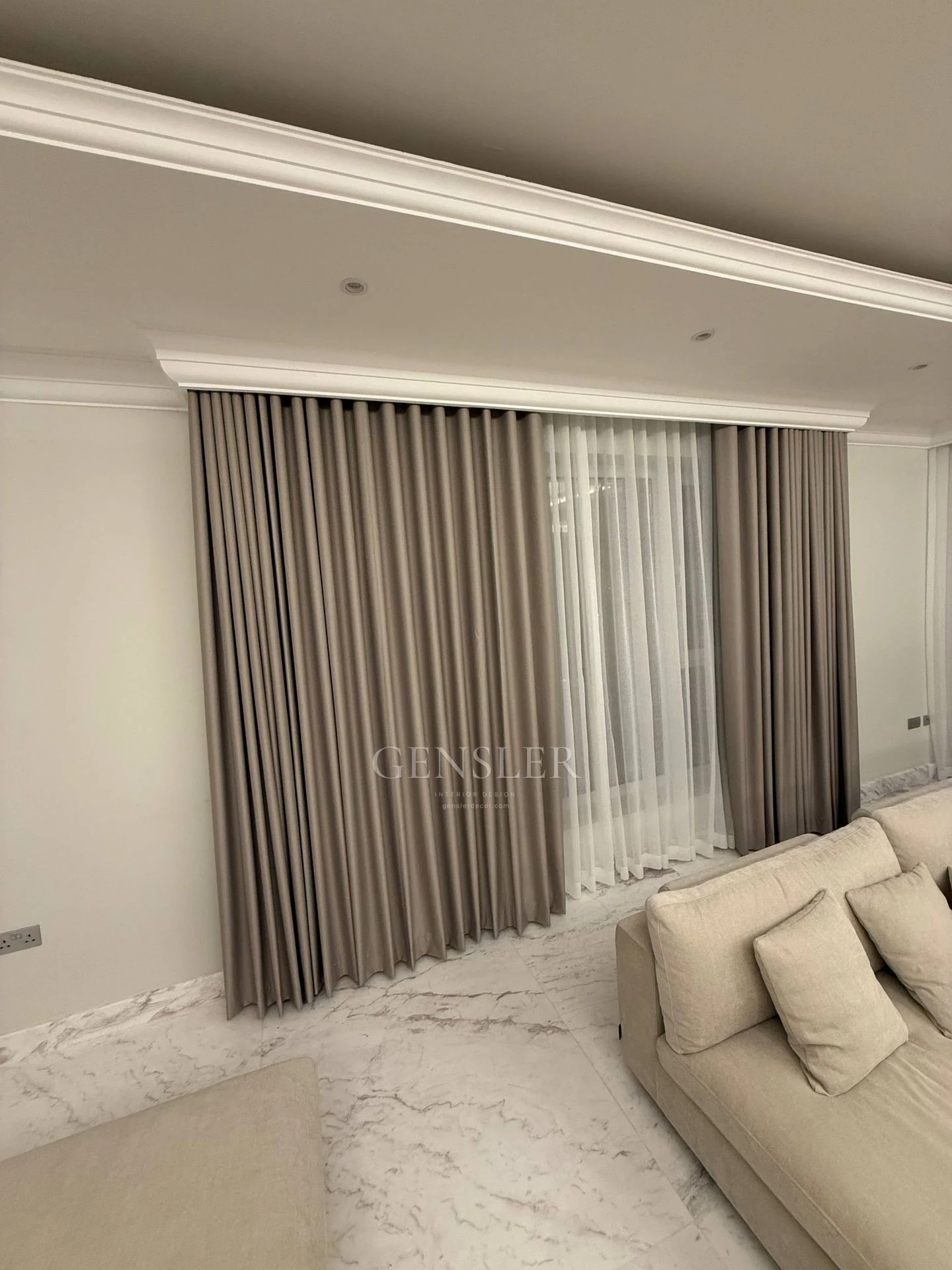 Grey full-height curtains and white sheers beside pale seating.