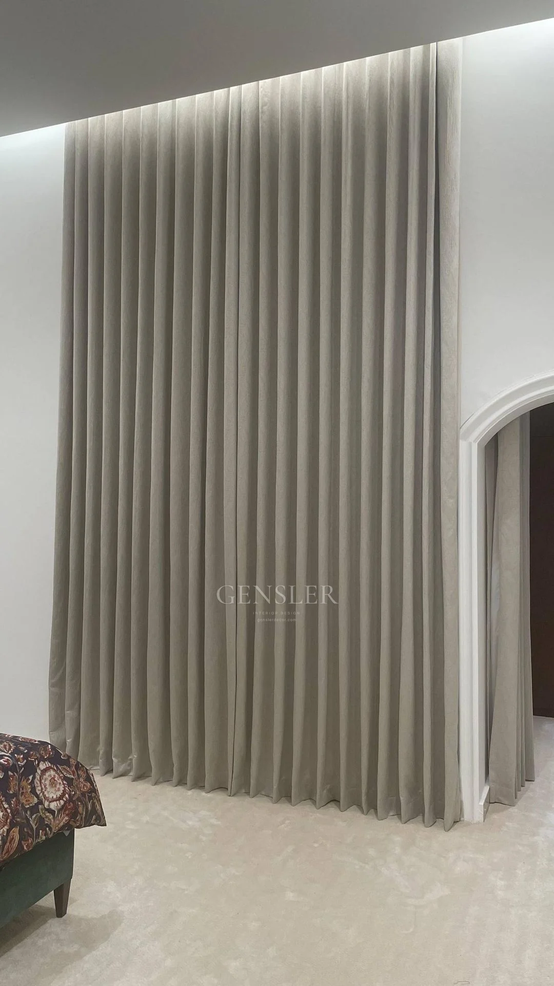 Full-height neutral curtain folds beneath concealed ceiling lighting.