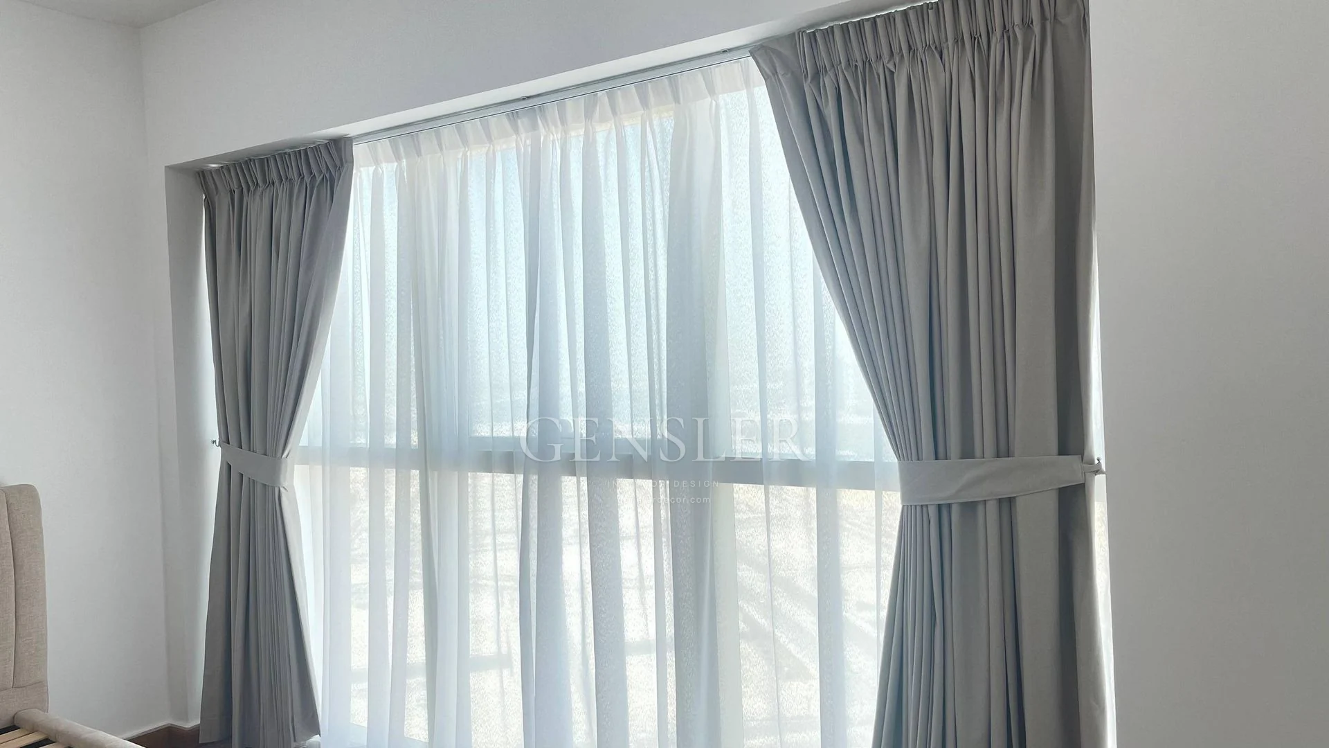 Grey tied-back curtains with a white sheer inner layer.