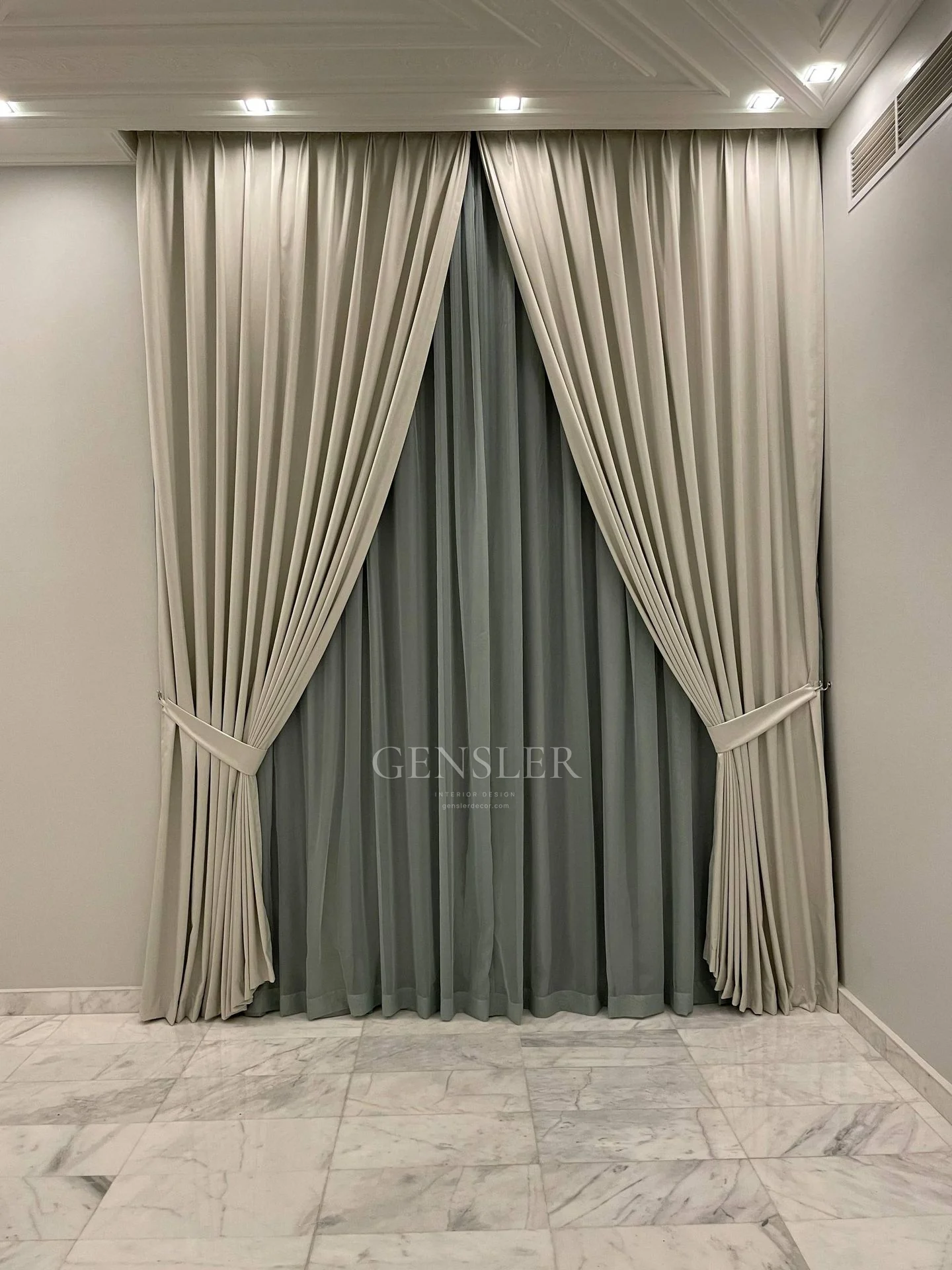 Layered grey curtains gathered at the sides of a tall window.
