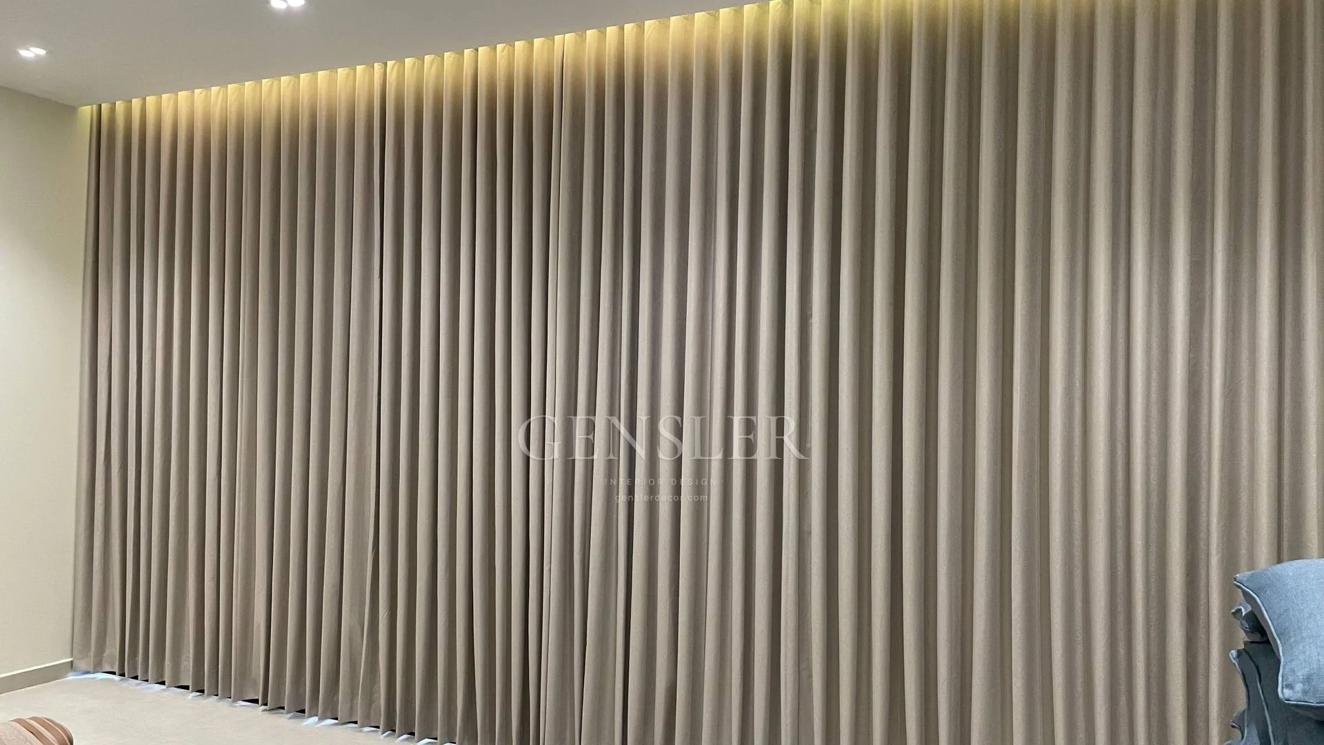 Neutral full-height curtain folds illuminated from above.