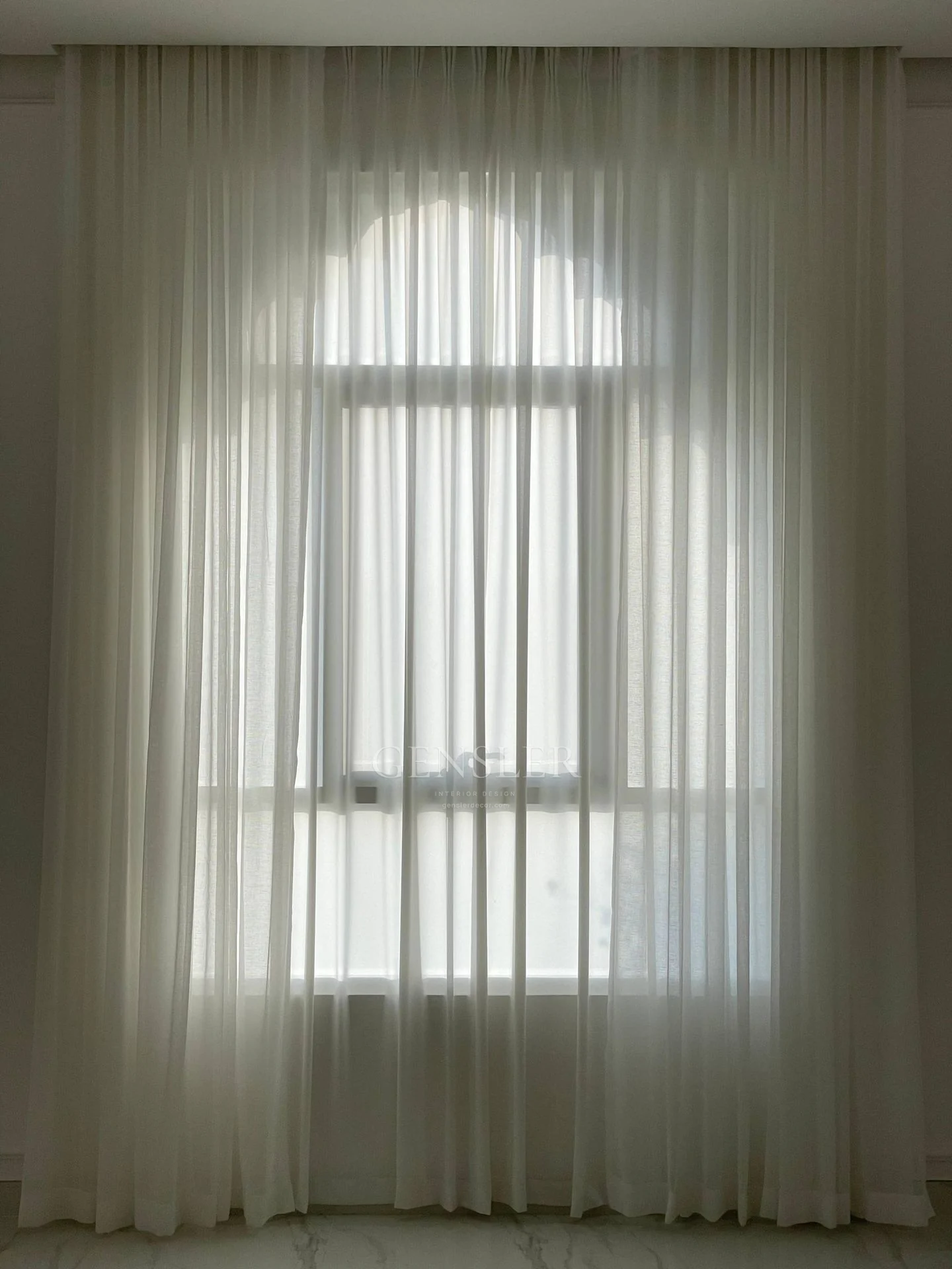 Arched window visible through full-height ivory sheers.