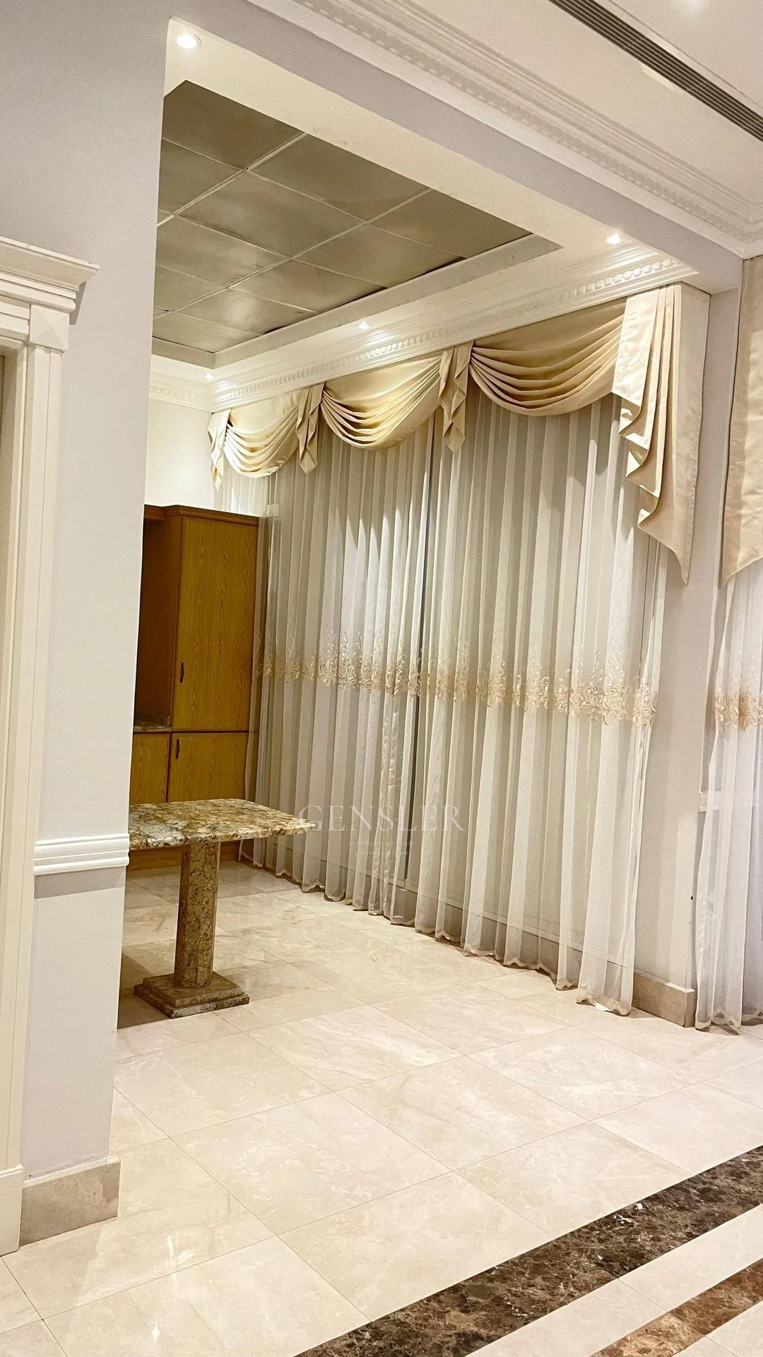 Ivory sheer curtains and decorative swags in an adjoining interior.