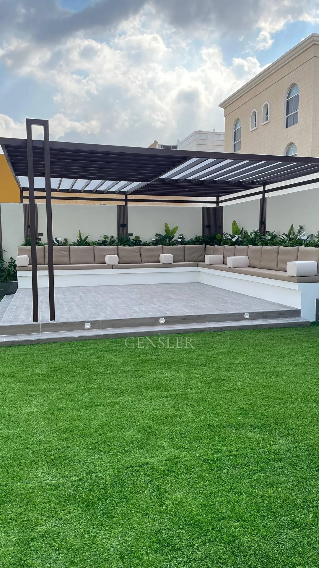 Garden pergola with pale seating and a green lawn surface.