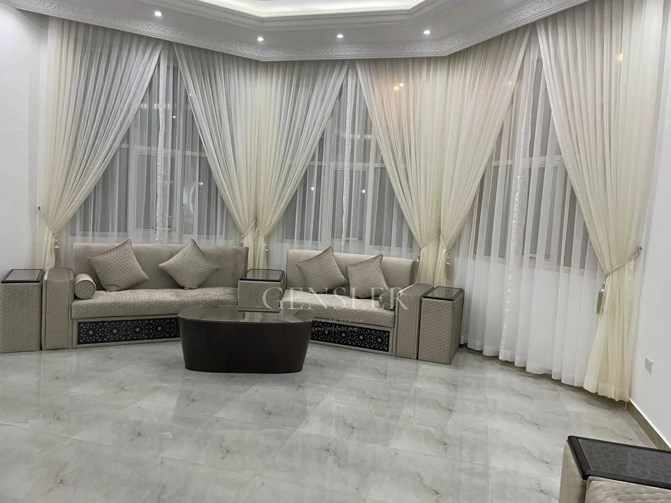 Ivory corner majlis with gathered curtains and white sheers.