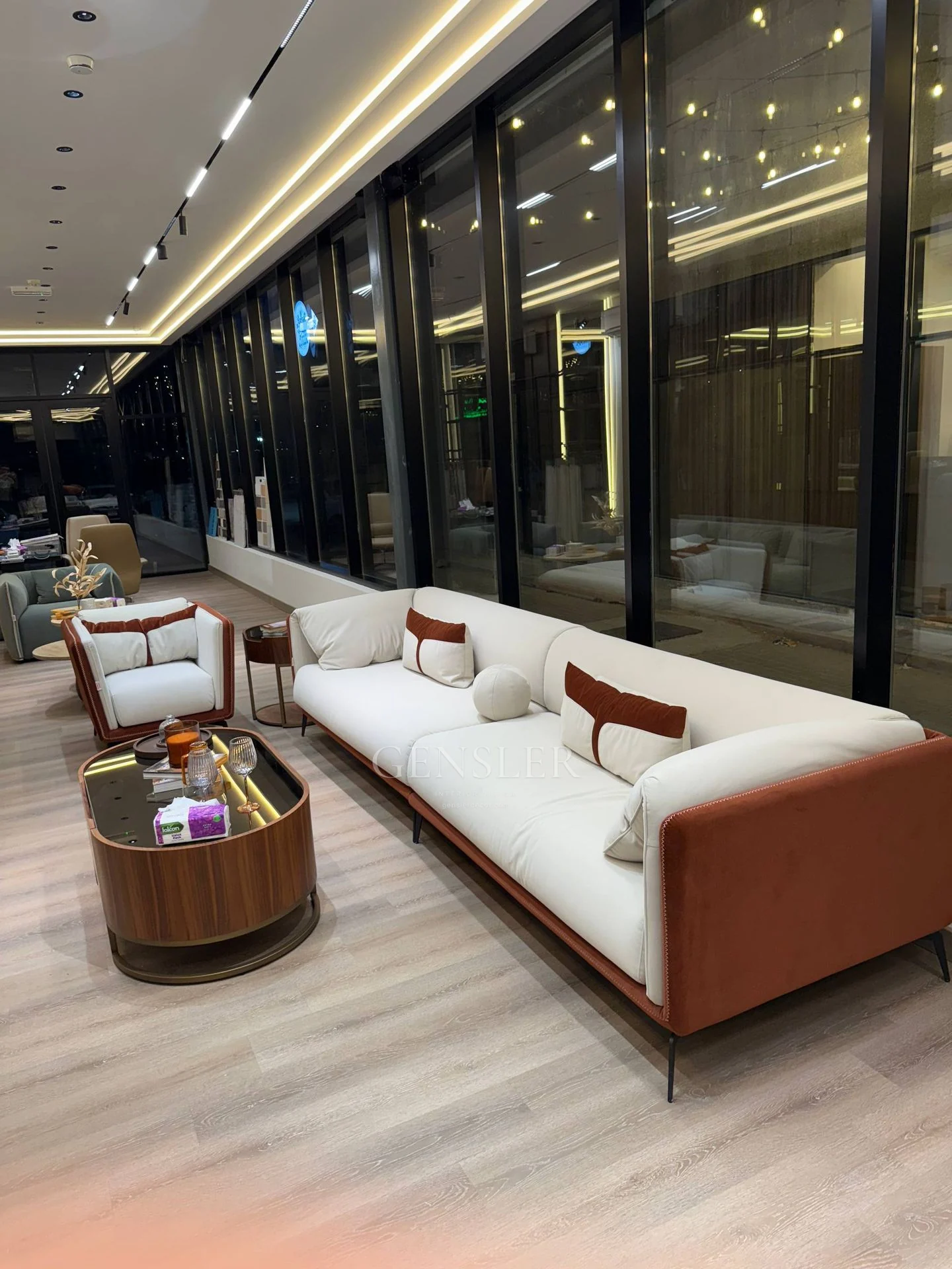 Side view of ivory seating and wood-tone tables beside tall glazing.
