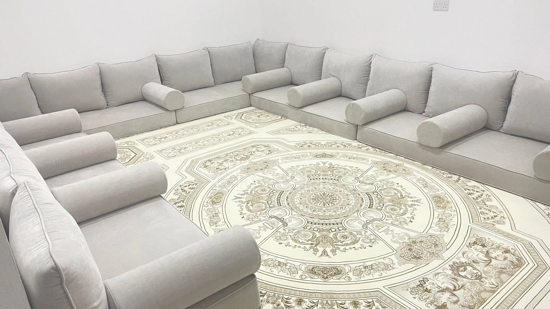 Grey floor seating around a cream rug with an ornamental medallion.