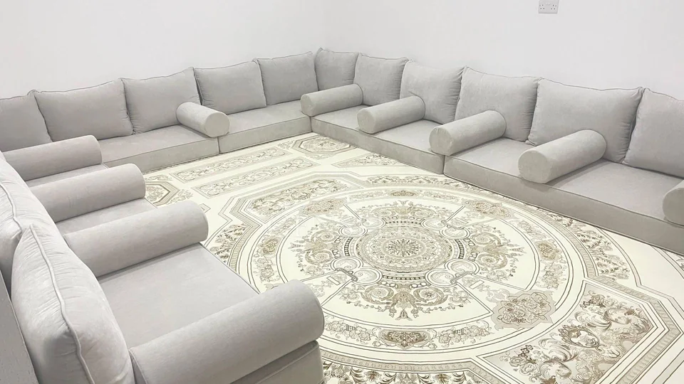 Grey floor seating around a cream rug with an ornamental medallion.