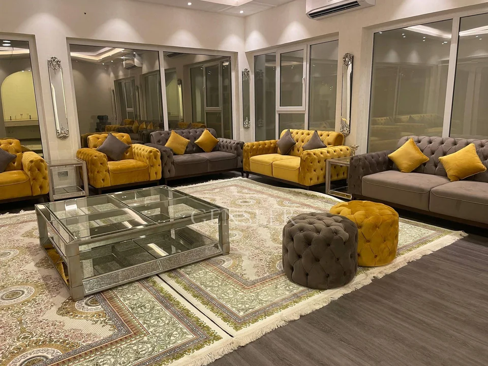 Grey and ochre tufted sofas, armchairs and stools around glass tables.