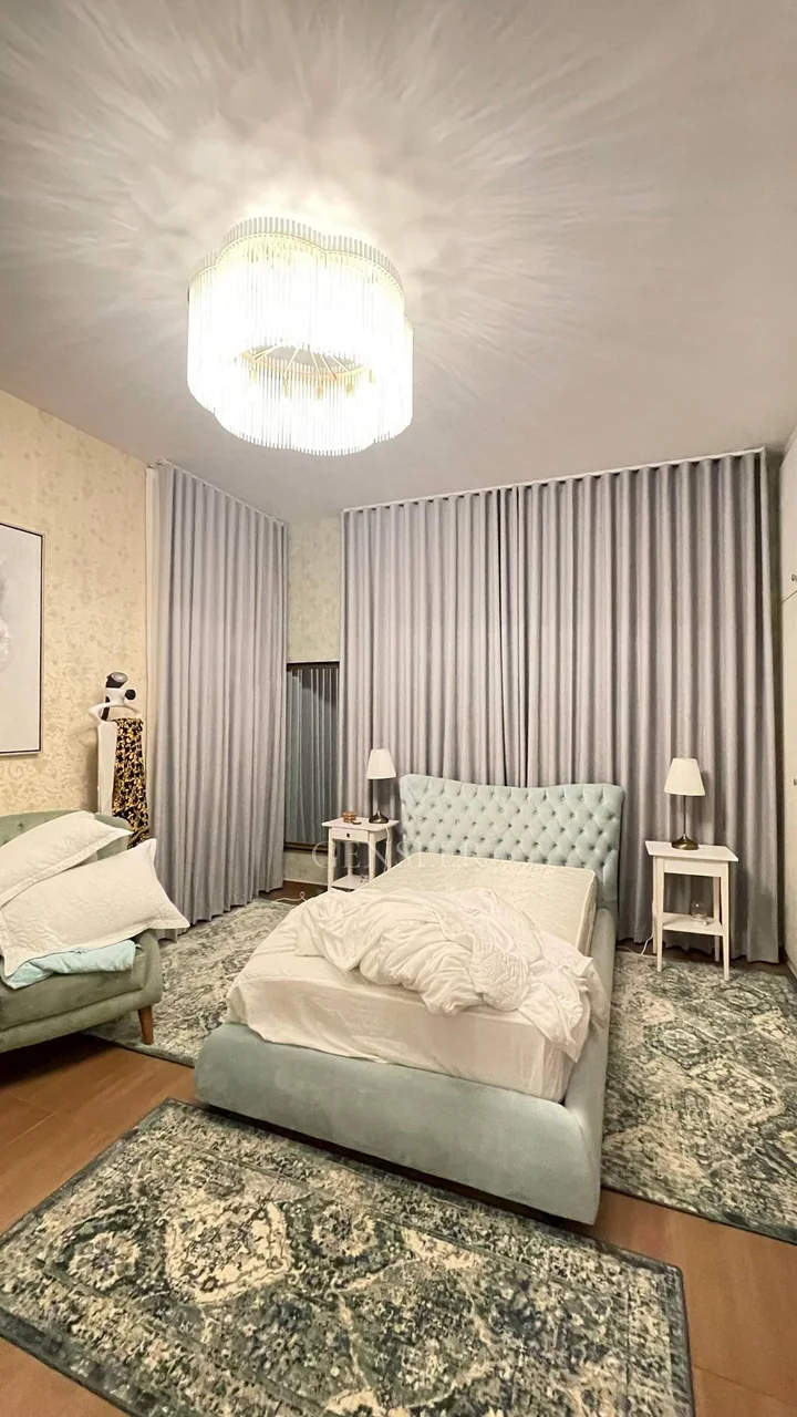 Pale blue upholstered beds with grey curtains and patterned rugs.