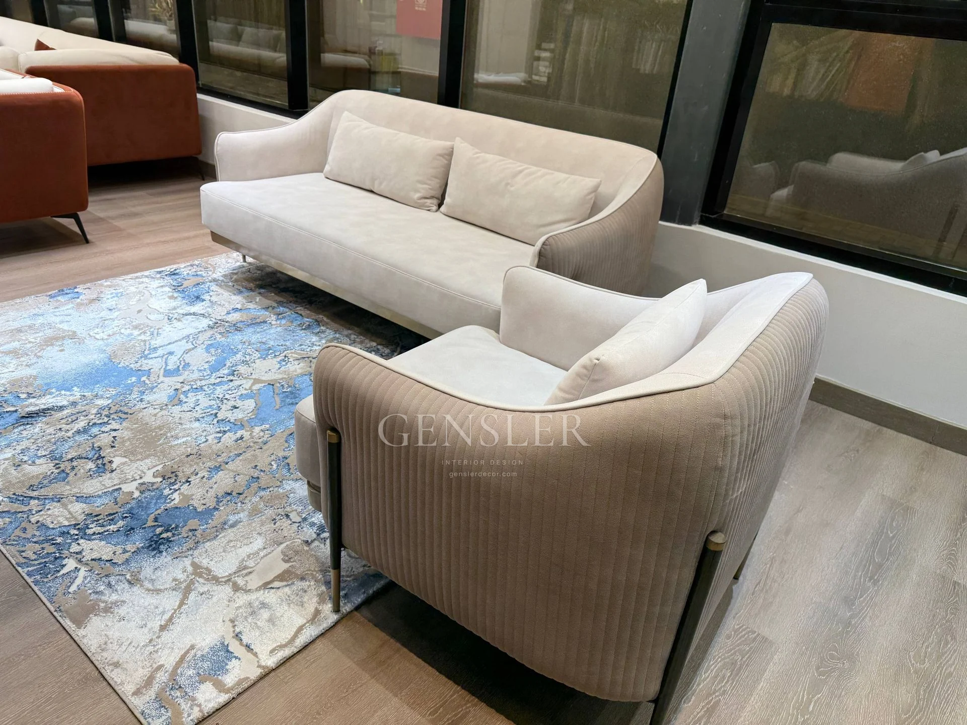 Cream sofa and ribbed-side armchair viewed across a blue patterned rug.