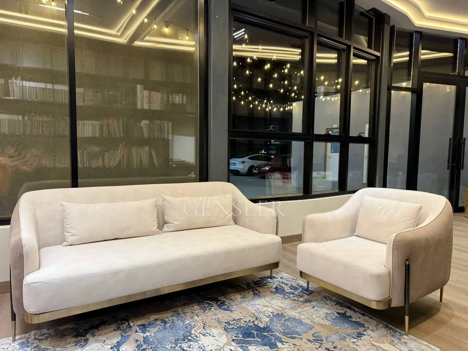 Cream sofa and matching armchair with curved sides and narrow legs.