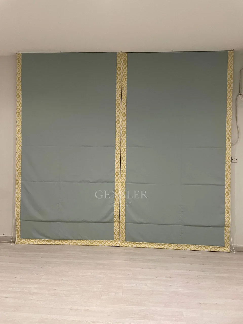 Muted green Roman blind with contrasting decorative gold-toned borders.
