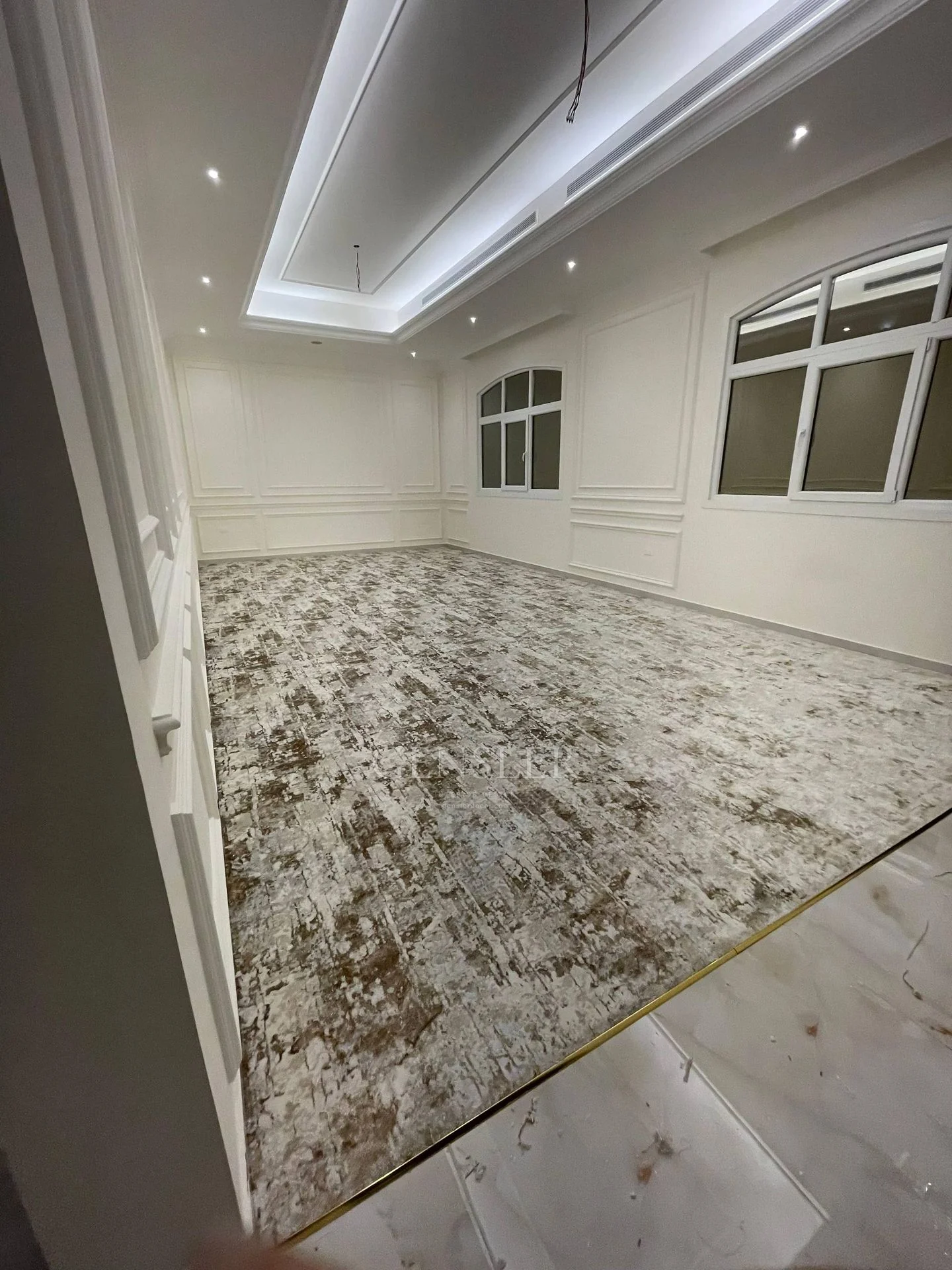 Grey-beige carpet in a long hall with recessed ceiling lighting.